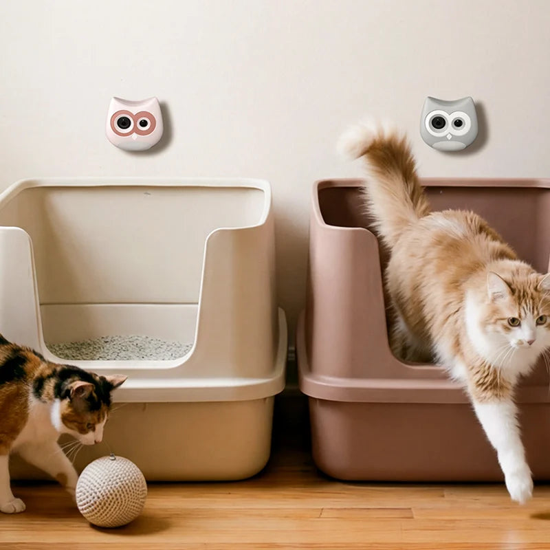 Two cats interacting with a modern cat litter box system on a wooden floor.