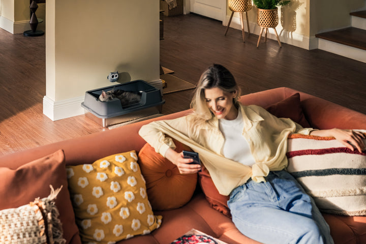 Woman relaxing at home while LitterLens monitors her cat's litter box activity